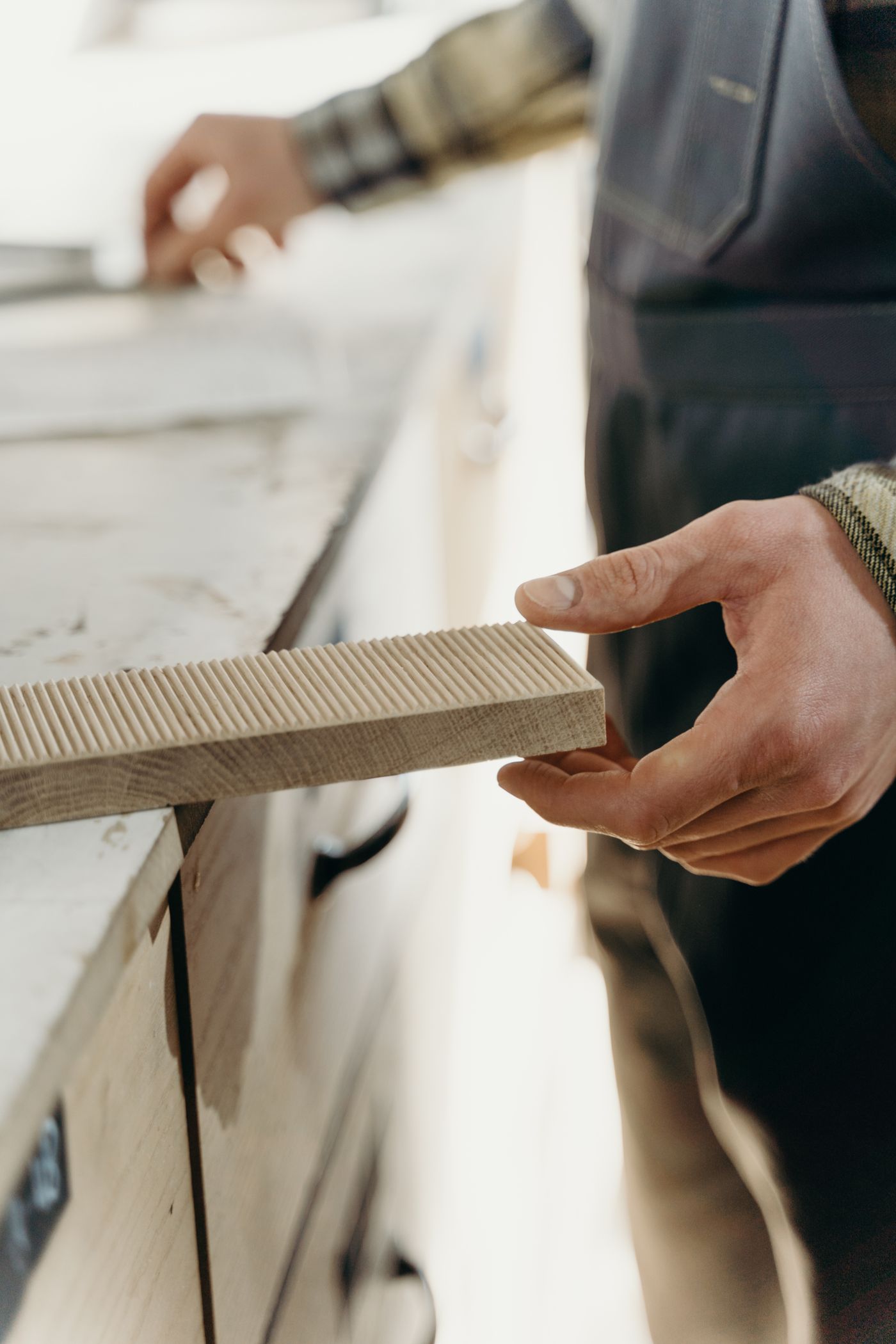 A carpenter inspecting the grooved edge and grain of a wooden board