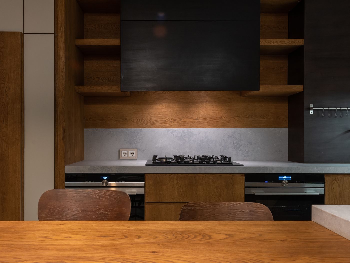 Wood kitchen cabinetry, open shelving, and a dining table in warm natural tones